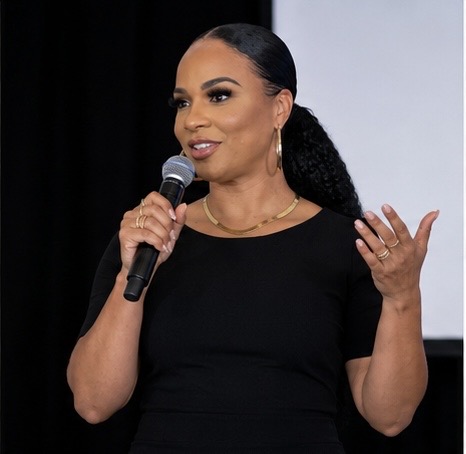 Maia Chaka speaking on stage with a microphone at a keynote event